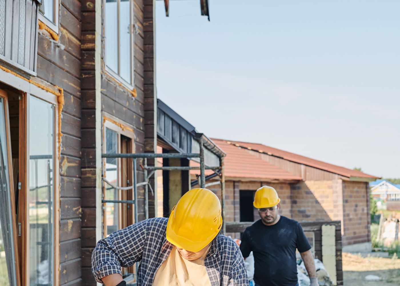 Two construction workers using tools at a timber building site