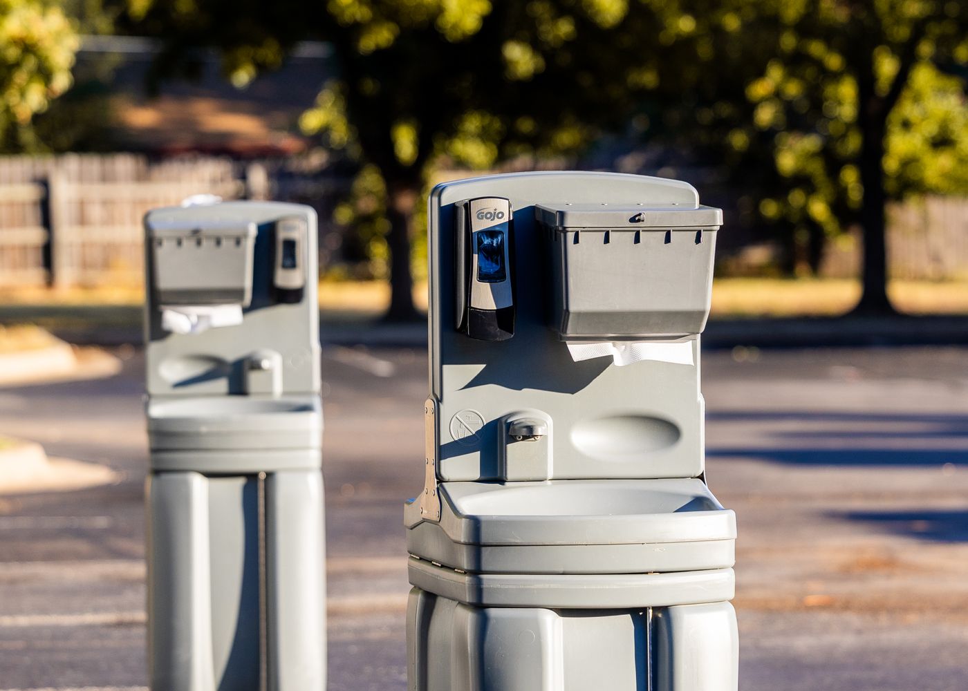 Two portable hand-wash stations on an outdoor paved area